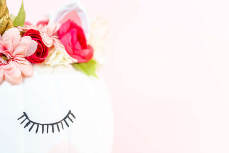 Craft pumpkin painted white and decorated with pink flowers as unicorn on pink background.の写真素材
