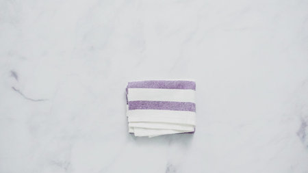 Folding blue and white patterned paper towels on marble surface.