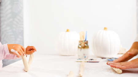 Step by step. Mother and daughter decorating Halloween craft pumpkin with unicorn theme.の写真素材