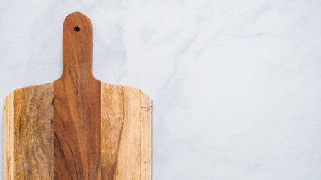 Rustic wood cutting board on marble kitchen counter.