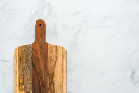 Rustic wood cutting board on marble countertop.の写真素材