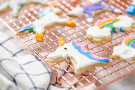 Unicorn shaped sugar cookies decorated by kids with royal icing on drying rack.の写真素材