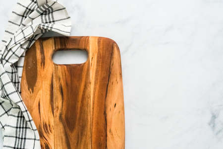 Rustic wood cutting board on marble countertop.の写真素材