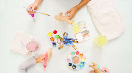 Step by step. Little girls painting paper mache unicorn with acrylic paint.の写真素材