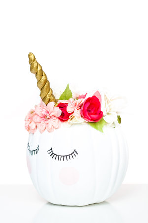 Craft pumpkin painted white and decorated with pink flowers as unicorn on white background.の写真素材