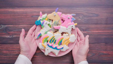 Unicorn shaped sugar cookies decorated with royal icing on pink plate.の写真素材