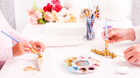 Mother and daughter decorating craft pumpkins with unicorn theme for Halloween.の写真素材