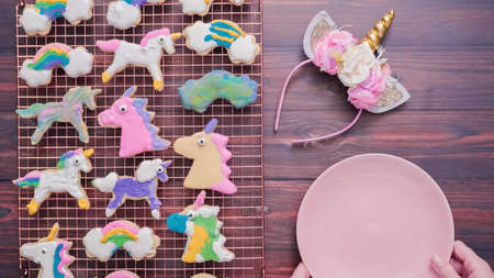 Unicorn shaped sugar cookies decorated with royal icing on pink plate.の写真素材