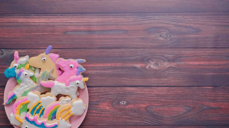 Unicorn shaped sugar cookies decorated with royal icing on pink plate.の写真素材