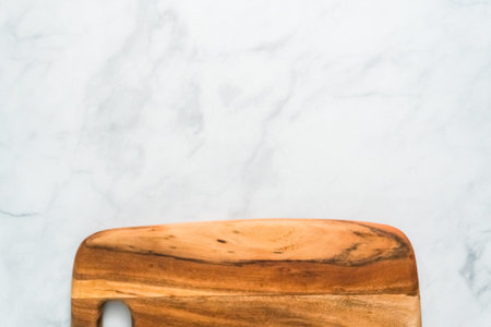 Rustic wood cutting board on marble countertop.