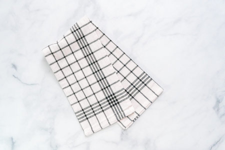 New kitchen towels with simple black pattern folded on marble counter.の写真素材