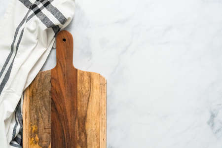 Rustic wood cutting board on marble countertop.の写真素材
