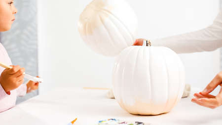 Step by step. Mother and daughter decorating Halloween craft pumpkin with unicorn theme.の写真素材