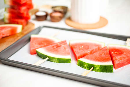 Sliced watermelon in triangle shapes on wooden sticks.の写真素材