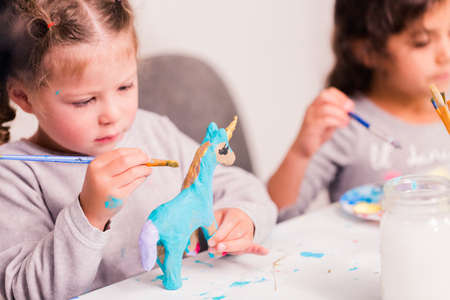 Little girls decorating small paper mache unicorn figurines.の写真素材