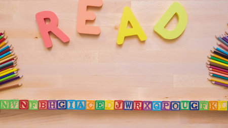 Word READ from multicolor wooden letters on wooden table.