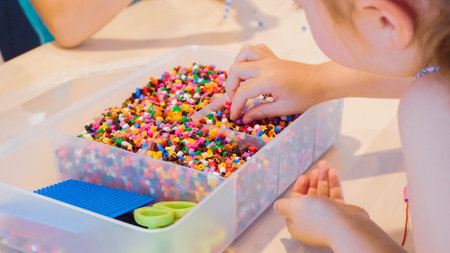 Little girl making bracelet from colorful kids beads.