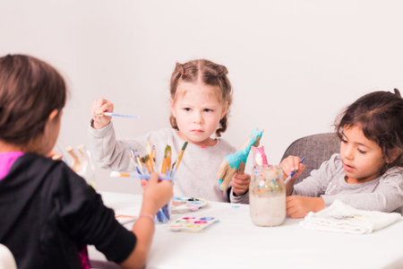 Little girls decorating small paper mache unicorn figurines.