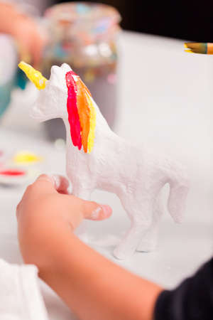 Girls decorating their small paper mache unicorns figurines at the unicorn extravaganza party.の写真素材