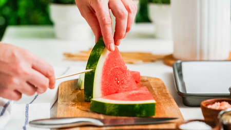 Step by step. Sliding the wood pop stick into the watermelon wage wedge to make watermelon ice pops.の写真素材
