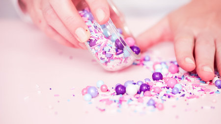 Colorful purple sprinkle blend on a pink background.