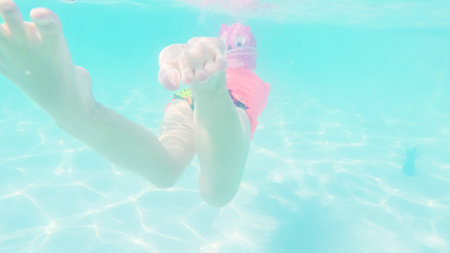 Little girl having fun swimming in outdoor pool in the Summer.