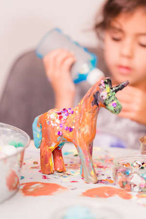Little girls decorating small paper mache unicorn figurines.の写真素材