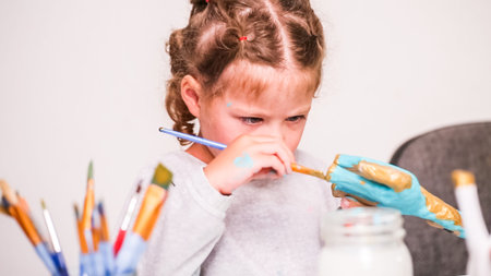 Little girls painting paper mache unicorn with acrylic paint.