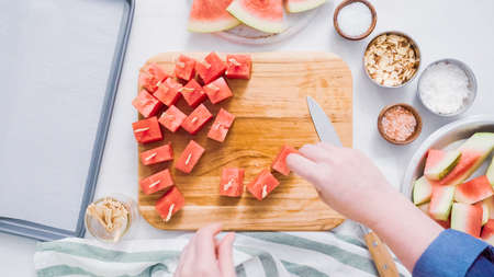 Slicing watermelon into cubes for preparing chocolate covered watermelon bites.の写真素材