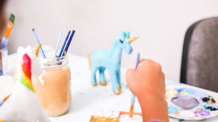 Little girls painting paper mache unicorn with acrylic paint.の写真素材