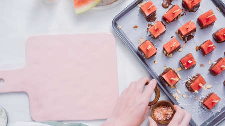 Dipping watermelon cubes into melted chocolate and garnishing with sea salt and almonds.の写真素材