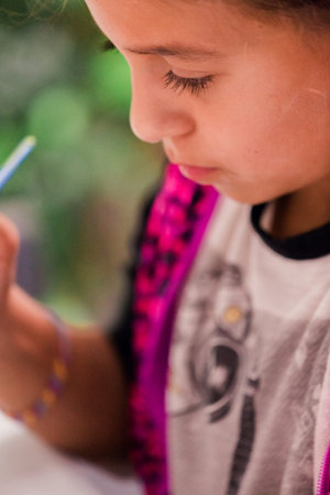 Little girls decorating small paper mache unicorn figurines.