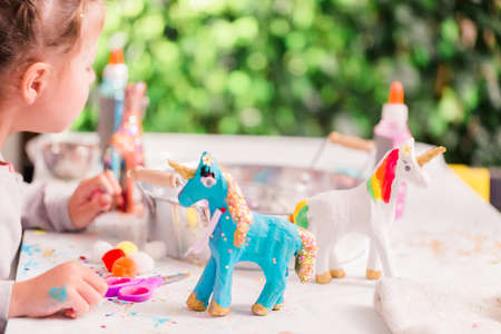 Little girls decorating small paper mache unicorn figurines.の写真素材