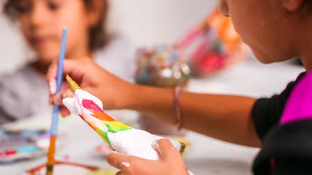 Little girls painting paper mache unicorn with acrylic paint.の写真素材