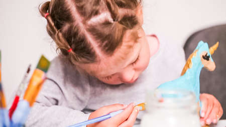 Little girls painting paper mache unicorn with acrylic paint.の写真素材