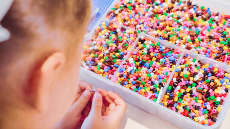 Little girl making bracelet from colorful kids beads.