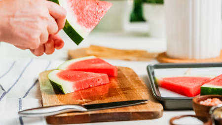 Step by step. Sliding the wood pop stick into the watermelon wage wedge to make watermelon ice pops.の写真素材