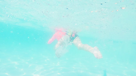 Little girl having fun swimming in outdoor pool in the Summer.