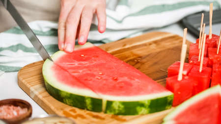 Slicing watermelon into cubes for preparing chocolate covered watermelon bites.の写真素材