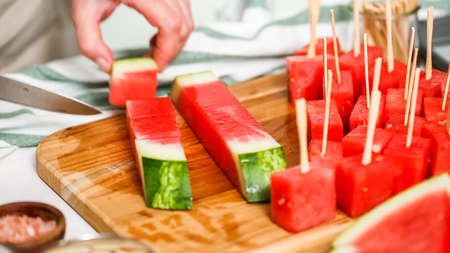 Slicing watermelon into cubes for preparing chocolate covered watermelon bites.の写真素材