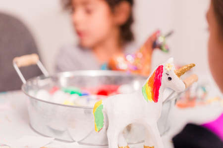 Little girls decorating small paper mache unicorn figurines.の写真素材