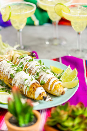 Grilling mexican street corn elote garnished with spices and fresh cilantro on a serving plate.