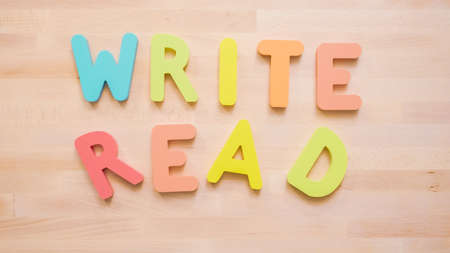 Words READ and WRITE from multicolor wooden letters on wooden table.の写真素材