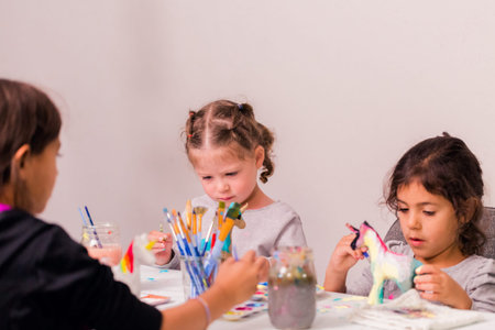 Little girls decorating small paper mache unicorn figurines.