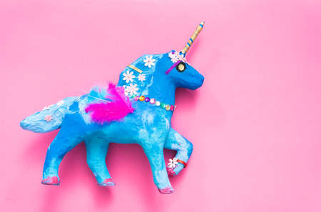 Kids craft. Painted blue and decorated with jewels and feathers paper mache unicorn.の写真素材