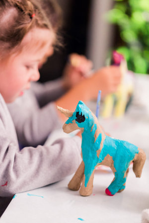 Little girls decorating small paper mache unicorn figurines.の写真素材
