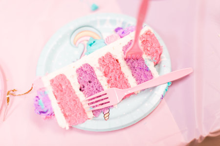 Sliced tall unicorn cake with pink and purple cake layers at little girl's birthday party.