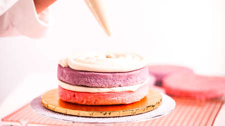Baker assembling pink and purple cake layer to make unicorn cake for little girl's birthday party.の写真素材