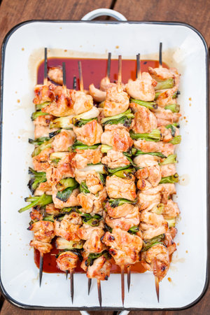 Chicken yakitori with scallions on white metal serving tray.の写真素材