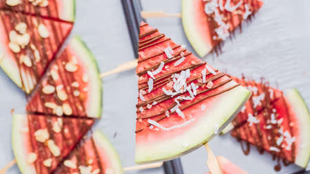 Step by step. Watermelon wedges garnished with chocolate and sea salt  on the stick on baking sheet.の写真素材